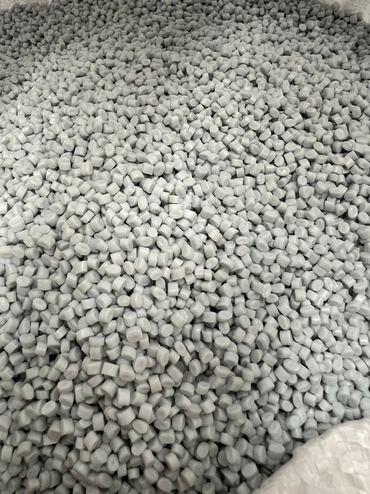 Close-up of numerous small gray plastic pellets grouped together.