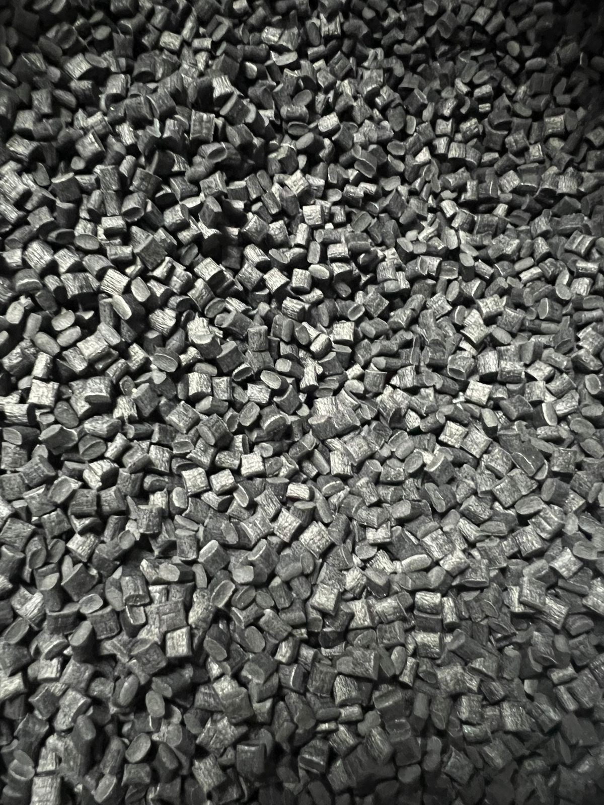 Close-up of a pile of small, black plastic pellets used in manufacturing.